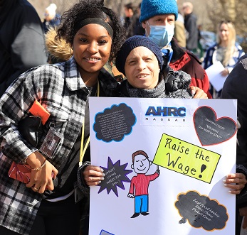 Two women at a rally holding up a sign saying 