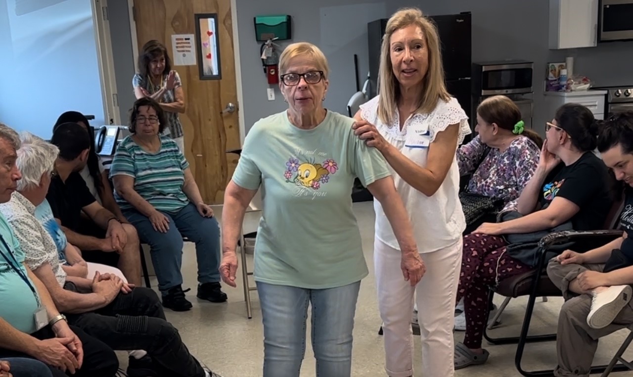 Marianne Barbera assists dance class attendee to perform Mic